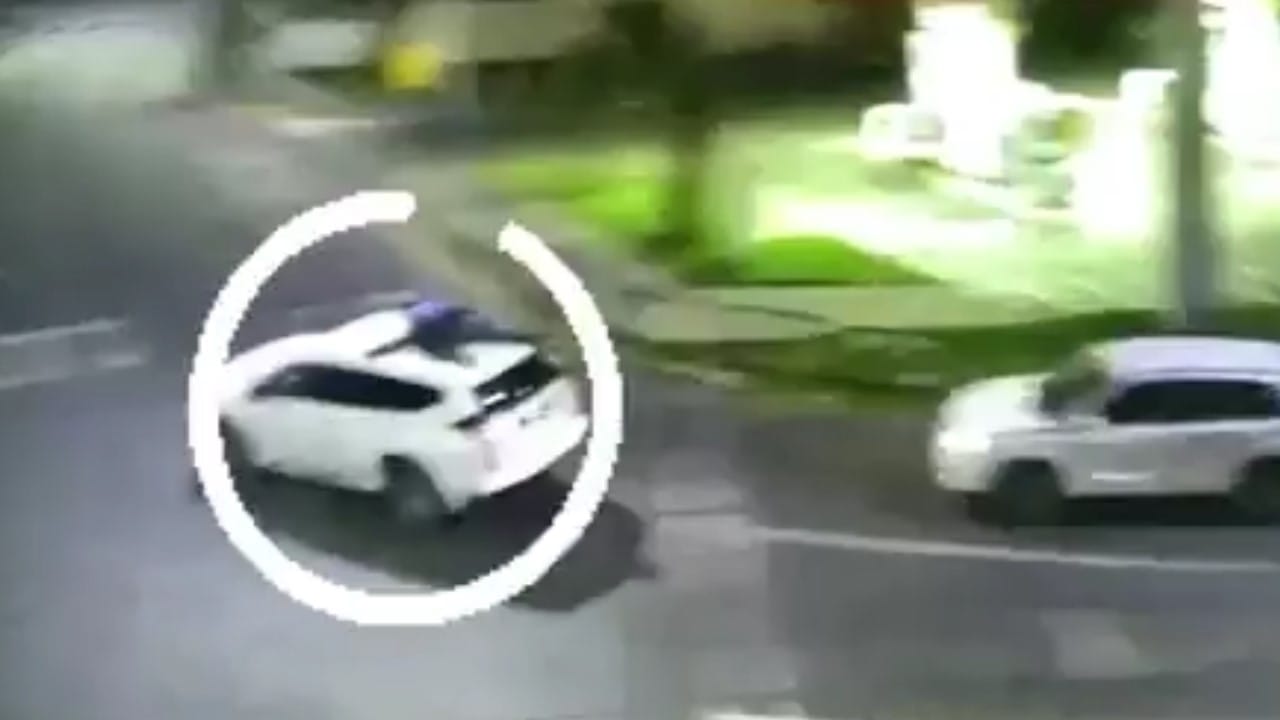Registran a delincuente escapando colgado del techo de un auto
